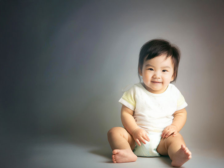 座ってとびきりの笑顔を見せる赤ちゃん