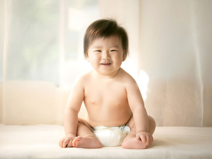 座ってとびきりの笑顔を見せる赤ちゃん