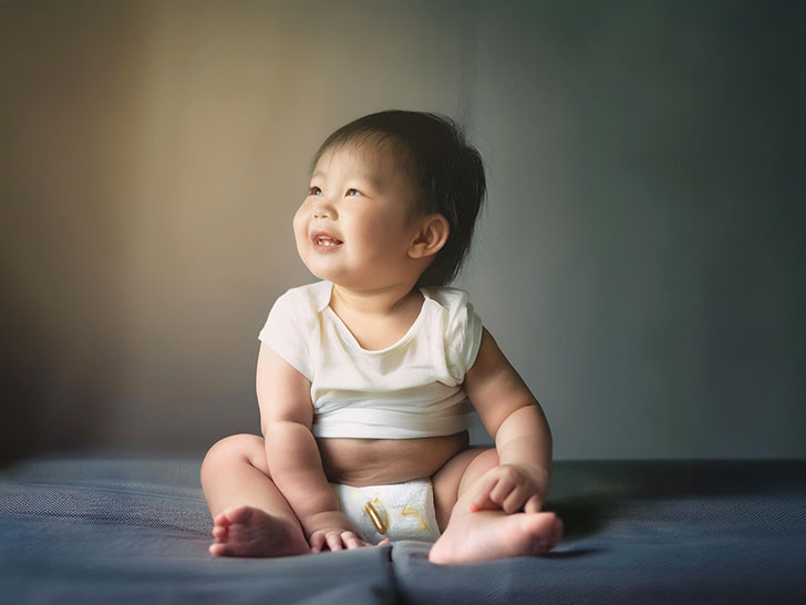 座ってとびきりの笑顔を見せる赤ちゃん