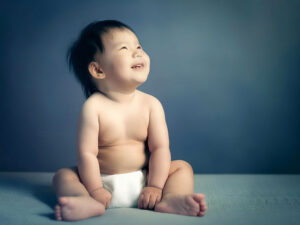 座ってとびきりの笑顔を見せる赤ちゃん