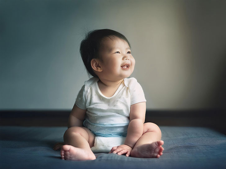 座ってとびきりの笑顔を見せる赤ちゃん