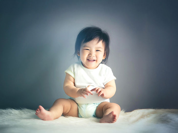 座ってとびきりの笑顔を見せる赤ちゃん