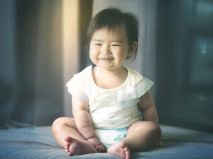 座ってとびきりの笑顔を見せる赤ちゃん