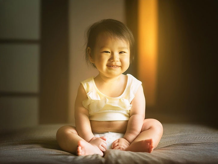 座ってとびきりの笑顔を見せる赤ちゃん