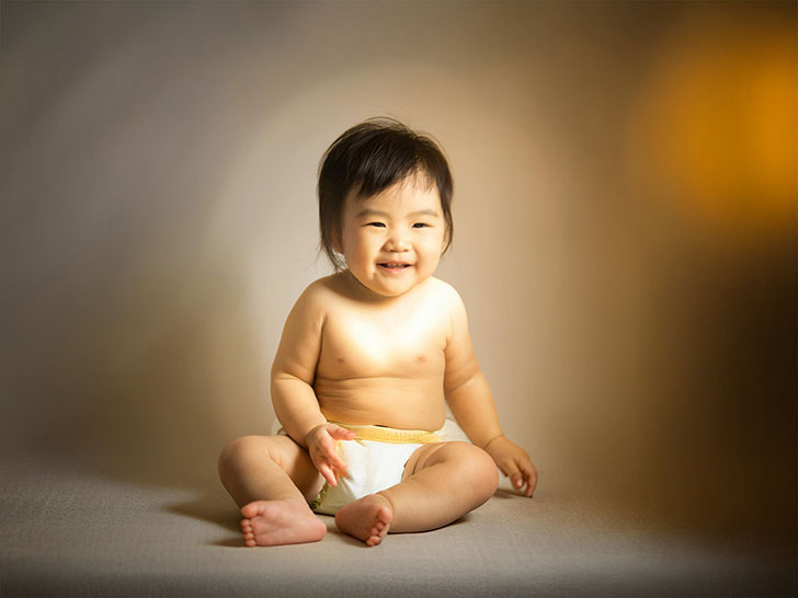 座ってとびきりの笑顔を見せる赤ちゃん