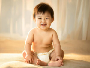 座ってとびきりの笑顔を見せる赤ちゃん