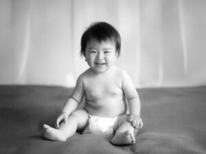 座ってとびきりの笑顔を見せる赤ちゃん