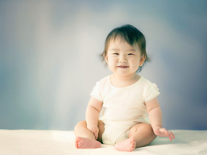 座ってとびきりの笑顔を見せる赤ちゃん