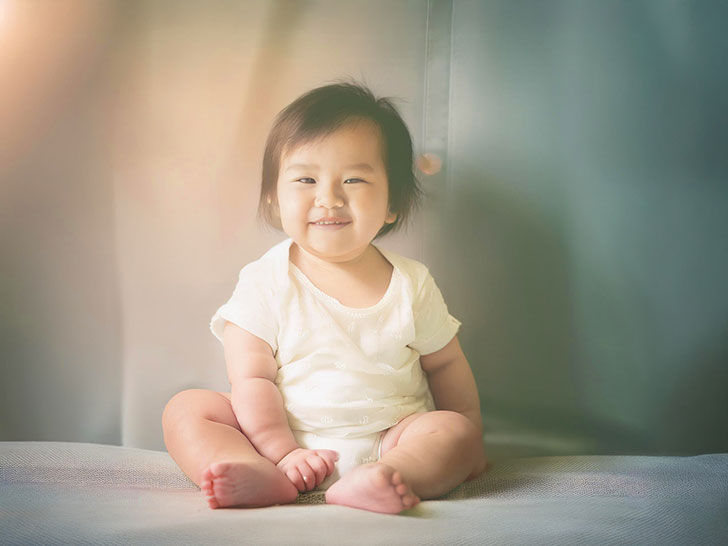 座ってとびきりの笑顔を見せる赤ちゃん