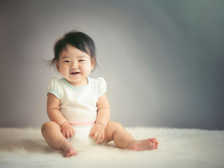 座ってとびきりの笑顔を見せる赤ちゃん