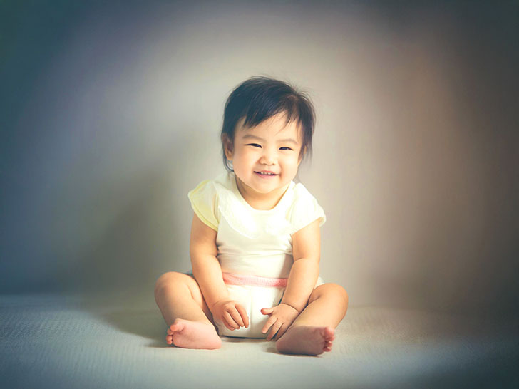 座ってとびきりの笑顔を見せる赤ちゃん
