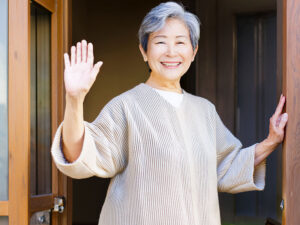 玄関先で手を振るシニア女性