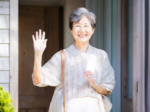 玄関先で手を振るシニア女性