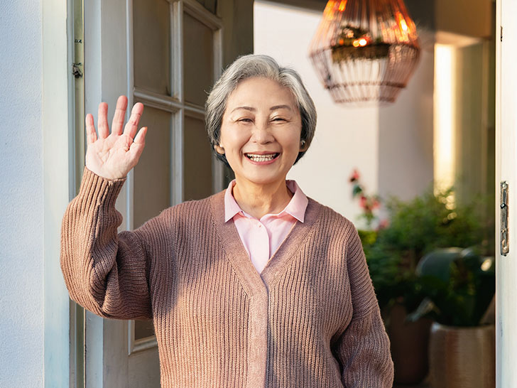 玄関先で手を振るシニア女性