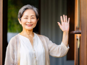 玄関先で手を振るシニア女性
