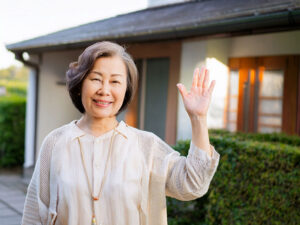 玄関先で手を振るシニア女性