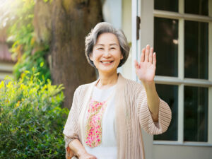 玄関先で手を振るシニア女性