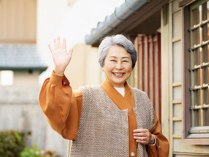 玄関先で手を振るシニア女性