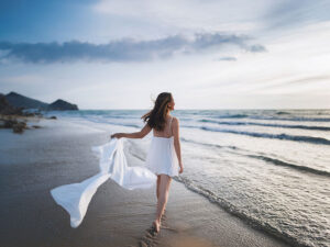白いドレスで海岸を歩く若い女性