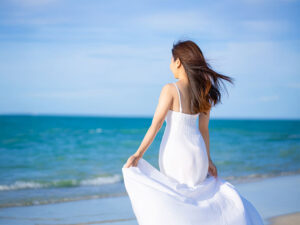 白いドレスで海岸を歩く若い女性