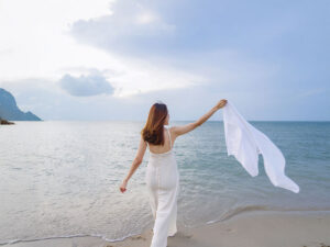 白いドレスで海岸を歩く若い女性