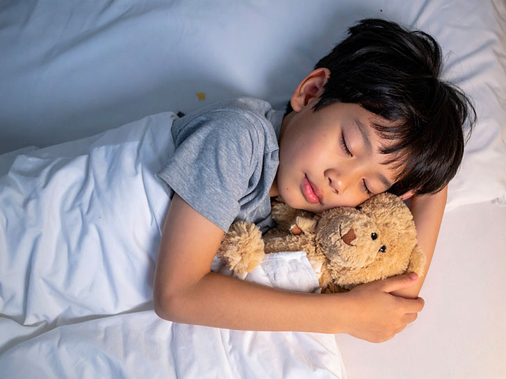 ベッドで眠る小さな男の子