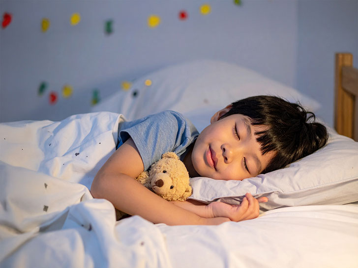 ベッドで眠る小さな男の子