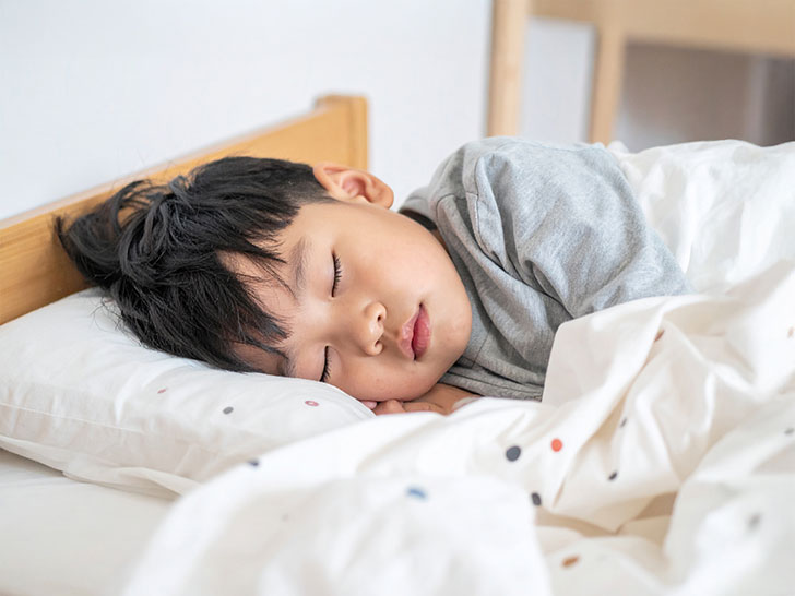 ベッドで眠る小さな男の子