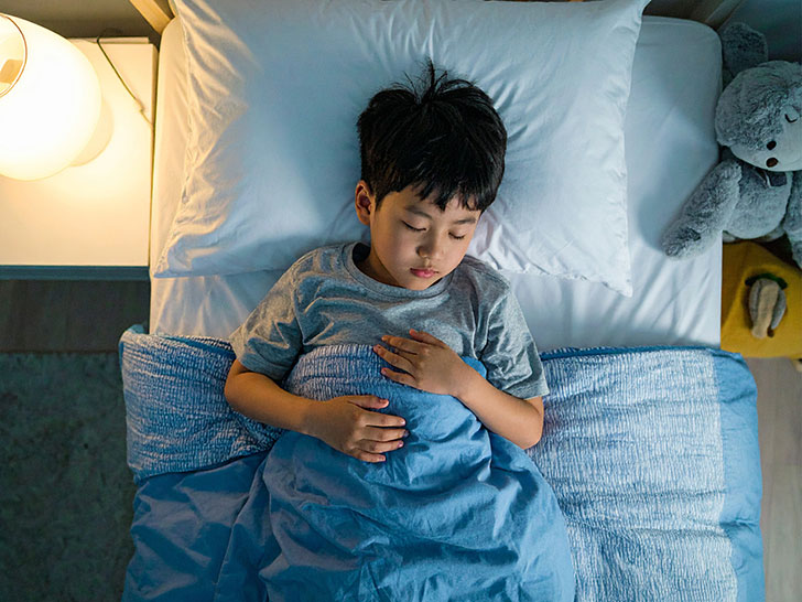 ベッドで眠る小さな男の子