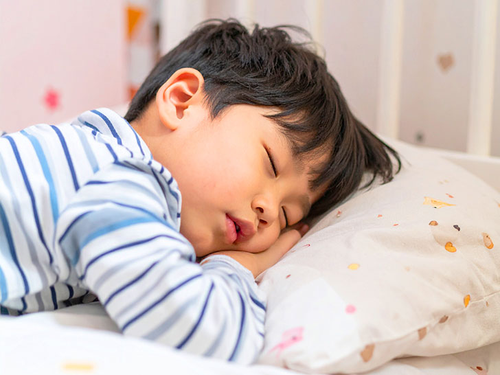 ベッドで眠る小さな男の子