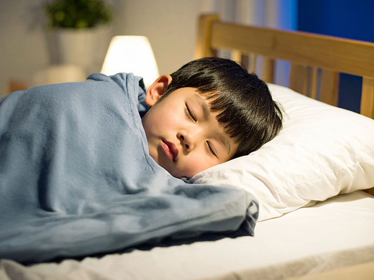 ベッドで眠る小さな男の子