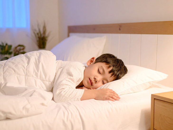 ベッドで眠る小さな男の子