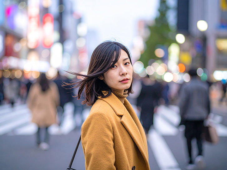 コートを着て街中に佇む若い女性