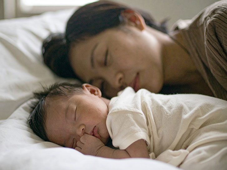 赤ちゃんと一緒に眠るお母さん