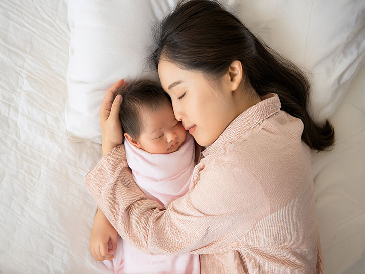 赤ちゃんと一緒に眠るお母さん