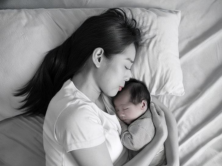 赤ちゃんと一緒に眠るお母さん