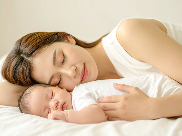 赤ちゃんと一緒に眠るお母さん