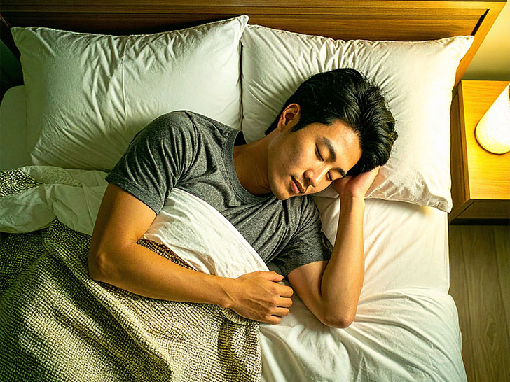 ベッドで眠る若い男性