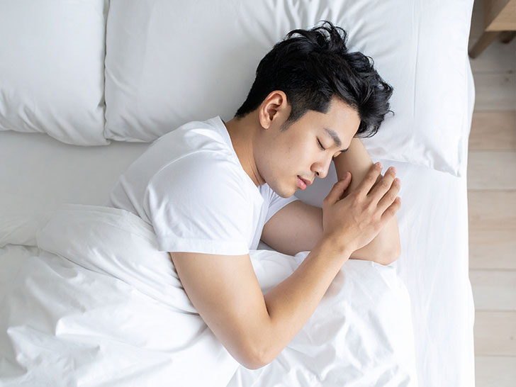 ベッドで眠る若い男性