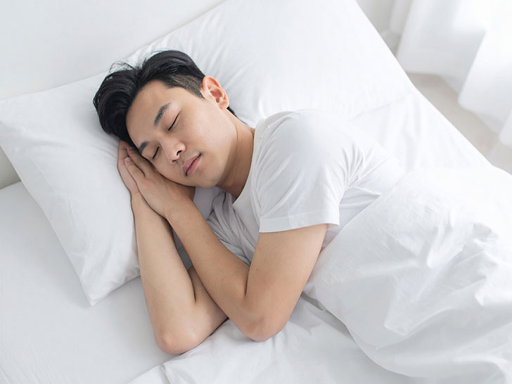 ベッドで眠る若い男性