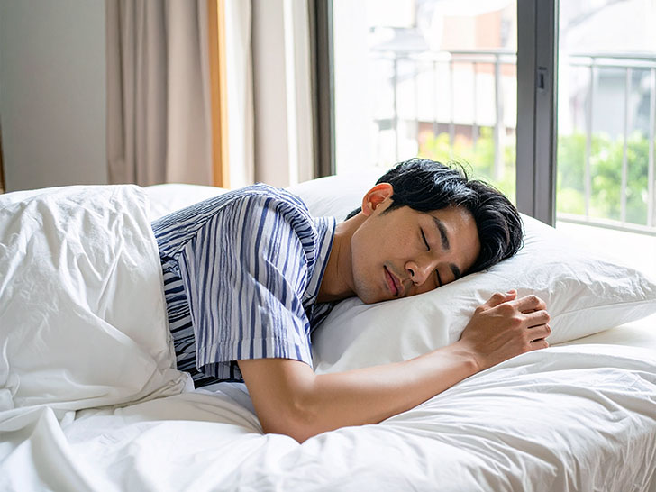 ベッドで眠る若い男性