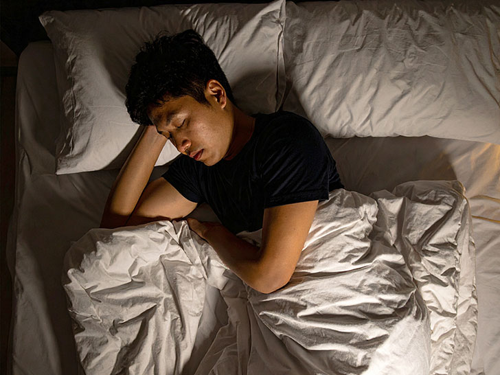 ベッドで眠る若い男性