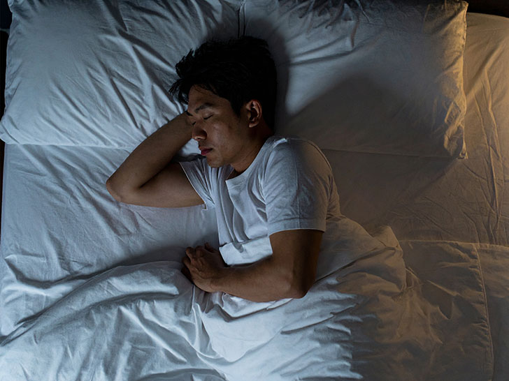 ベッドで眠る若い男性