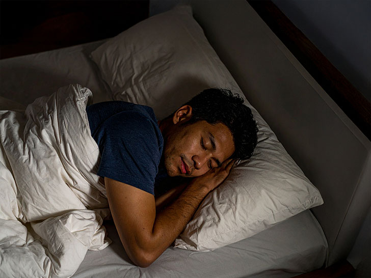 ベッドで眠る若い男性