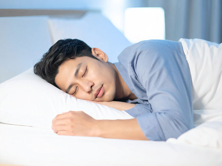 ベッドで眠る若い男性