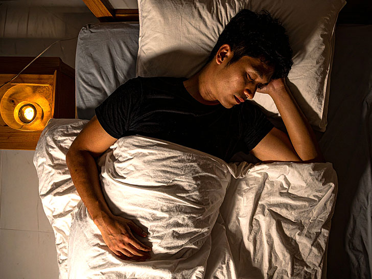 ベッドで眠る若い男性