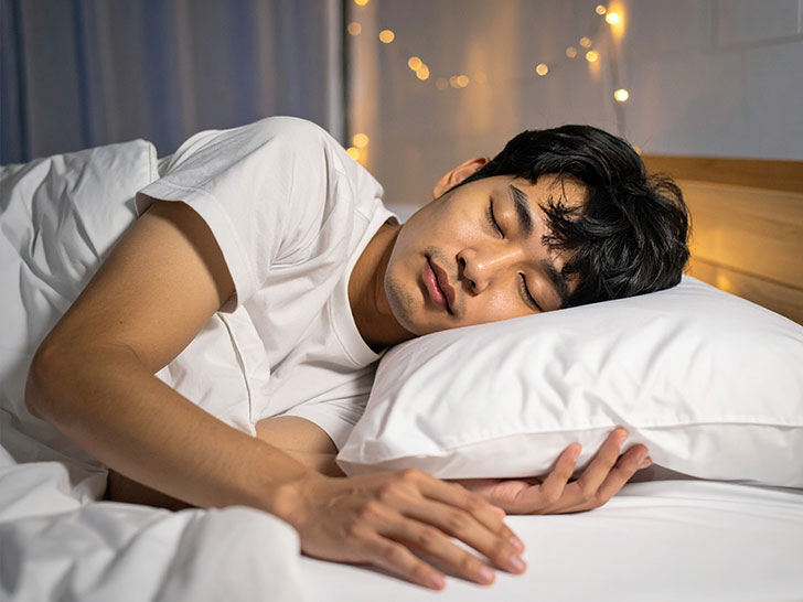 ベッドで眠る若い男性