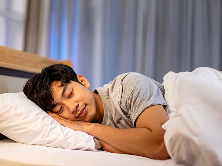 ベッドで眠る若い男性