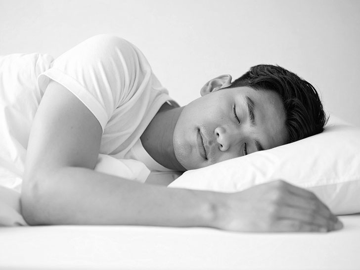 ベッドで眠る若い男性