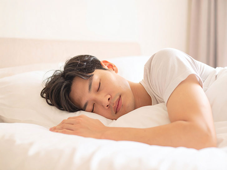 ベッドで眠る若い男性
